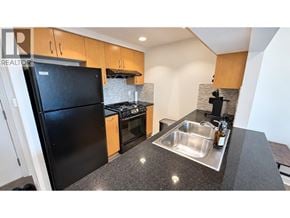 Vancouver apartment for rent - A modern kitchen with a black fridge and a granite countertop.