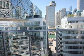 Toronto (Waterfront Communities) condo for rent - A view of a cityscape with a building in the foreground and a clear blue sky above.