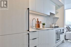 Toronto (Church-Yonge Corridor) condo for rent - A modern kitchen with white cabinets and a black refrigerator.