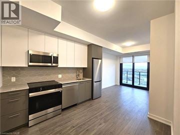 Kitchener condo for rent - A modern kitchen with stainless steel appliances and wooden flooring.