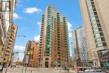 Ottawa condo for rent - A tall building with many windows is in the middle of a city street.