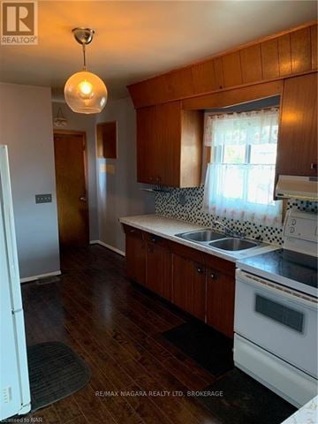 Welland (Welland Downtown) apartment for rent - A kitchen with wooden cabinets and a white fridge.