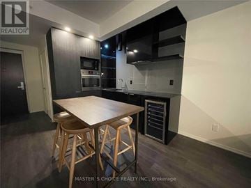 Toronto (Bay Street Corridor) condo for rent - A kitchen with a table and chairs in the foreground and a refrigerator in the background.