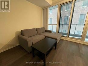Toronto (Bay Street Corridor) condo for rent - A grey couch and coffee table in a room with a window.
