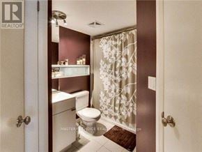 Toronto (Bay Street Corridor) condo for rent - A bathroom with a toilet, sink, and shower curtain.