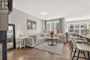 Ottawa townhouse for rent - A living room with a white sofa set and a coffee table with a vase of flowers on it.