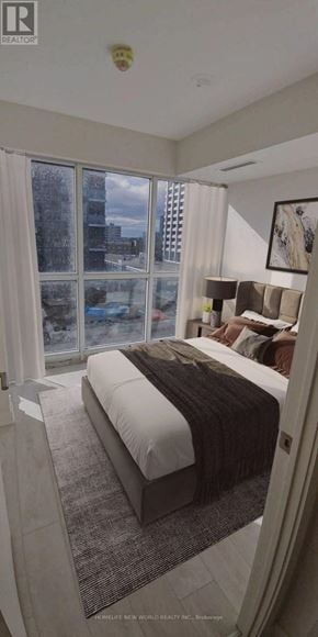 Toronto (Flemingdon Park) condo for rent - A bedroom with a large bed and a view of the city outside the window.