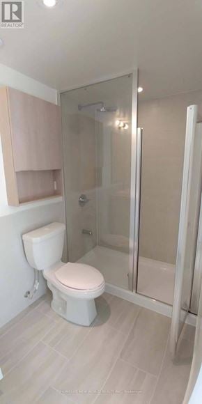 Toronto (Flemingdon Park) condo for rent - A white toilet in a bathroom with a glass shower door.