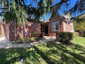 London North (North A) townhouse for rent - A house with a red brick exterior and a white window is surrounded by greenery.