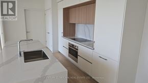 Toronto (Annex) condo for rent - A modern kitchen with white cabinets and a wooden hood.