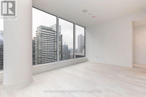 Toronto (Waterfront Communities) condo for rent - A large, empty room with a view of the cityscape outside the window.