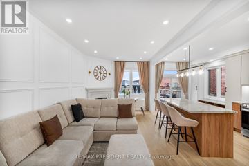 Brampton (Bram East) apartment for rent - A modern living room with a large sectional sofa and a kitchen area with a bar stool.