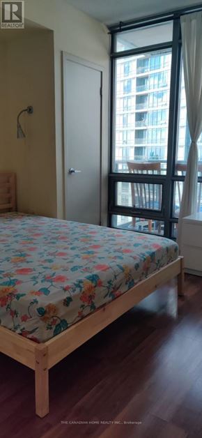 Toronto (Waterfront Communities) condo for rent - A bedroom with a large bed and a window overlooking a building.