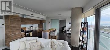 Toronto (Waterfront Communities) condo for rent - A living room with a couch and a large window overlooking an airport.