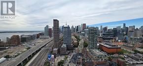 Toronto (Waterfront Communities) condo for rent - A cityscape with a large body of water in the background and a bridge crossing over it.