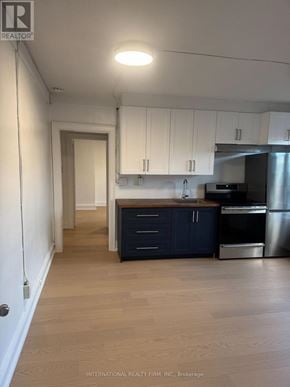 Toronto (Dufferin Grove) multi-family for rent - A kitchen with white cabinets and a wooden island.
