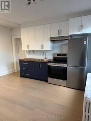 Toronto (Dufferin Grove) multi-family for rent - A kitchen with white cabinets and a stainless steel refrigerator.