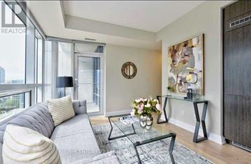 Toronto (Willowdale East) condo for rent - A living room with a grey couch, a glass coffee table, and a painting on the wall.