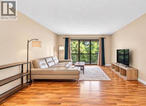 Maple Ridge apartment for rent - A living room with a couch, a television, and a window with a view of trees.