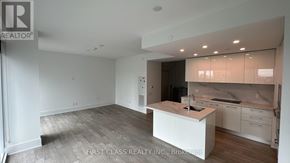 Toronto (Church-Yonge Corridor) condo for rent - A real estate company is showcasing a modern kitchen with a white island and wooden flooring.