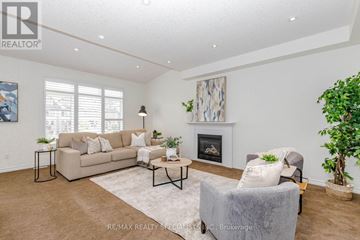 Guelph (Victoria North) apartment for rent - A living room with a beige couch, a grey armchair, a fireplace, and a painting on the wall.