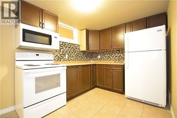 St. Catharines apartment for rent - A kitchen with white appliances and brown cabinets.