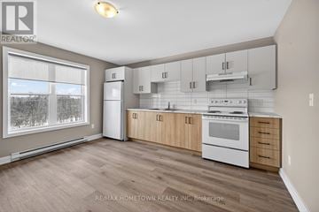 South Dundas condo for rent - A kitchen with white appliances and wooden cabinets.