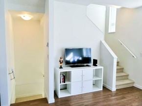 Surrey townhouse for rent - A television is on a stand in a room with a staircase.