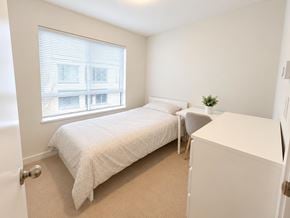 Surrey townhouse for rent - A bedroom with a bed, chair, and window.
