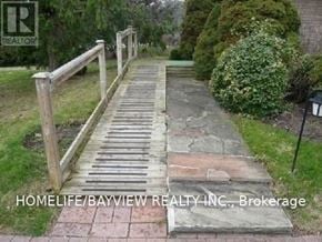Richmond Hill (South Richvale) apartment for rent - A wooden staircase with a railing on the left side and a hedge on the right side.