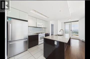 Burnaby apartment for rent - A modern kitchen with a stainless steel refrigerator and black countertops.