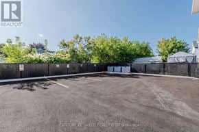 Cornwall triplex for rent - A parking lot with a fence and trees in the background.