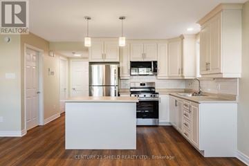 Cornwall triplex for rent - A kitchen with white cabinets and a wooden floor.