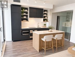 Toronto (Bay Street Corridor) condo for rent - A modern kitchen with a black refrigerator and wooden bar stools.