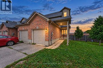 Kitchener townhouse for rent - A red car is parked in front of a brick house with a garage.