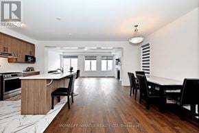 Innisfil apartment for rent - A modern kitchen with wooden floors and a dining area with black chairs.