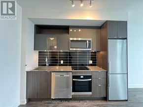 Toronto (Waterfront Communities) condo for rent - A modern kitchen with stainless steel appliances and wooden cabinets.
