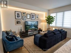 Thorold (Rolling Meadows) apartment for rent - A living room with a blue couch, a television, and a plant.