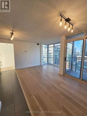 Toronto (Waterfront Communities) condo for rent - A room with wooden flooring and a large window overlooking a cityscape.