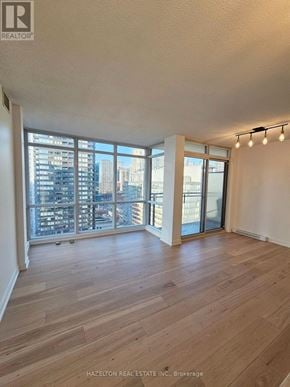 Toronto (Waterfront Communities) condo for rent - A room with wooden flooring and a view of the city through large windows.