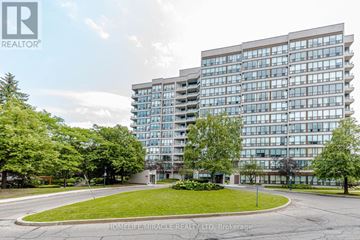 Brampton (Queen Street Corridor) condo for rent - A modern building with a glass facade is surrounded by a well-maintained lawn and trees.