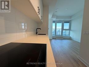 Toronto (Banbury-Don Mills) condo for rent - A kitchen with a black countertop and white tiled walls.