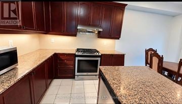 Brampton (Sandringham-Wellington) apartment for rent - A kitchen with brown cabinets and a granite countertop.