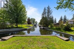 Georgina (Keswick North) duplex for rent - A serene canal surrounded by lush greenery and trees under a clear blue sky.