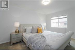 Mississauga (Meadowvale Village) townhouse for rent - A bedroom with a large bed, a nightstand with a lamp, and a window.
