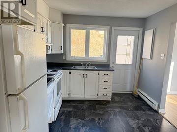 St. John's multi-family for rent - A kitchen with a white refrigerator and cabinets.
