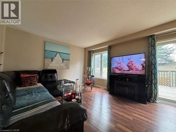 Kitchener townhouse for rent - A living room with a black leather couch and a television.