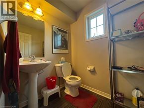 Kitchener townhouse for rent - A bathroom with a toilet, sink, and a red bucket.