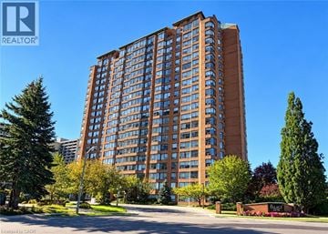 Burlington condo for rent - A tall building with a brown facade stands in front of a clear blue sky.