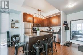 Toronto (Waterfront Communities) condo for rent - A modern kitchen with dark wood floors and stainless steel appliances.